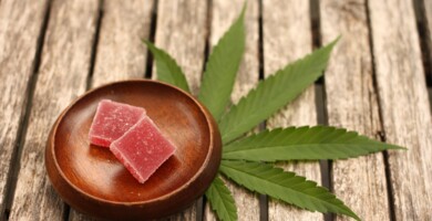 suessigkeit_in_einer_schale_daneben_cannabis_blatt_auf_holzbohlen