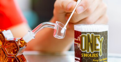 Hand die ein Wattestäbchen mit Cannabiskonzetrat in ein Dabbing Rig gibt