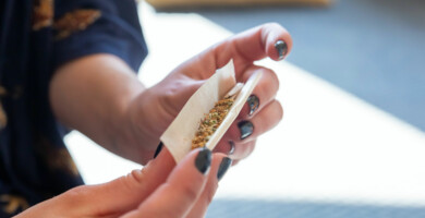 Frau die einen Joint rollt mit Sonnenschein im Hintergrund