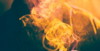 rauchender_joint_in_orangenem_gegenlicht_mit_person_im_hintergrund