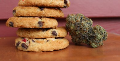Space Cookies neben einer Cannabisblüte auf einem Holztisch