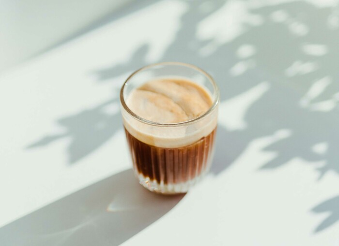 eine_tasse_kaffee_auf_einem_weissen_tisch_mit_schatten_einer_pflanze