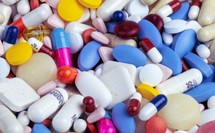 Diverse bunte und weiße Pillen auf einem Haufen liegend