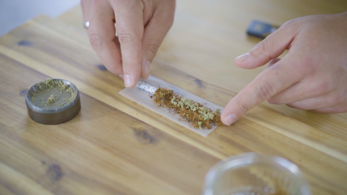 Zwei Hände die einen Joint drehen und einen Filter in dem Joint platzieren