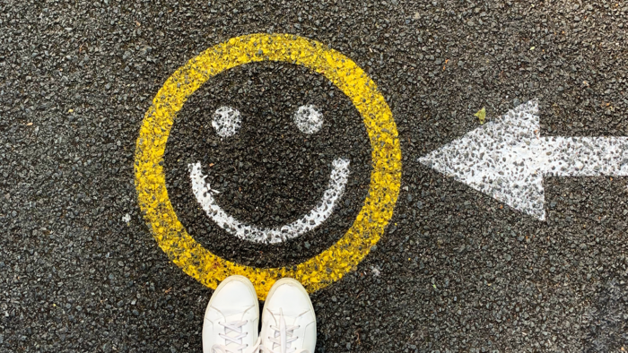 Straße auf welcher ein Smiley aufgemalt ist und ein paar Füße welche davor stehen
