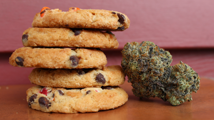 Space Cookies neben einer Cannabisblüte auf einem Holztisch