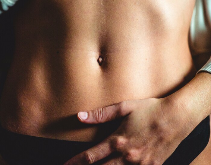 bauch_einer_frau_mit_einer_hand_die_den_bauch_haelt