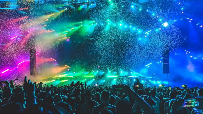 Bunte Lichtershow auf einem Festival mit vielen Menschen im Vordergrund