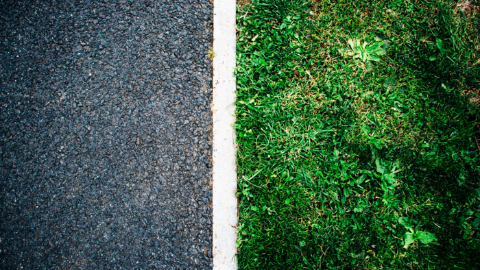 Aufnahme eines Straßenrandes mit einer weißen Linie in der Mitte zwischen dem Asphalt und einem Grünstreifen