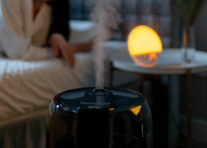 Stationärer Vaporizer im Schlafzimmer mit einem Leuchtwecker im Hintergrund