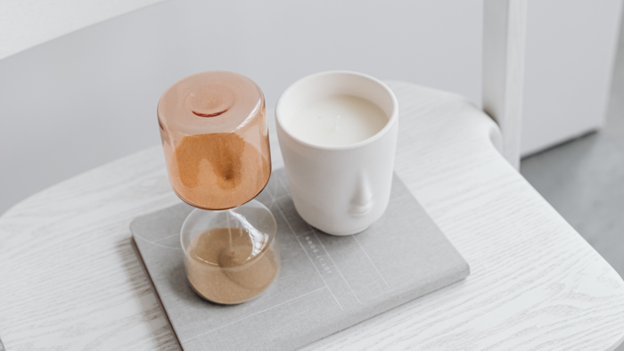 Sanduhr neben einer Tasse mit Milch auf einem hellen Tisch