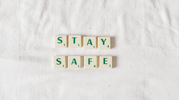 Buchstabenplättchen die die Wörte Stay und Safe auf einem weißen Laken liegend bilden
