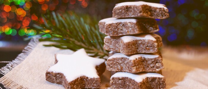 zimtsterne_auf_jute_vor_beleuchtetem_weihnachtshintergrund