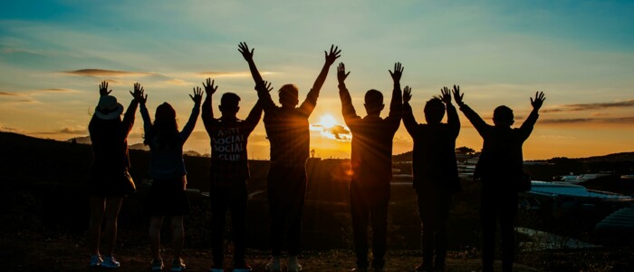 menschen_im_gegenlicht_bei_sonnenuntergang_mit_erhobenen_haenden