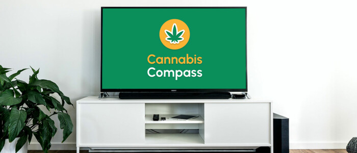 Szene eines TV-Tisches mit einem Fernseher auf welchem das Cannabis Compass Logo zu sehen ist