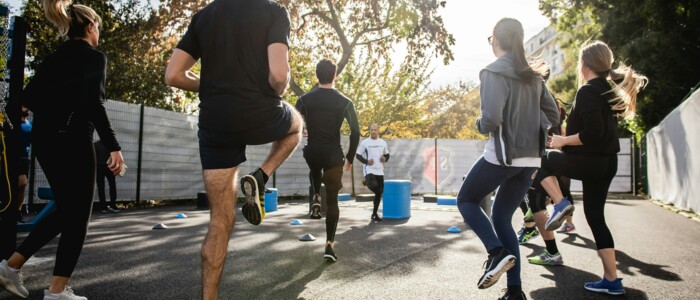 gruppe_sportlicher_junger_menschen_im_gegenlicht_mit_trainer
