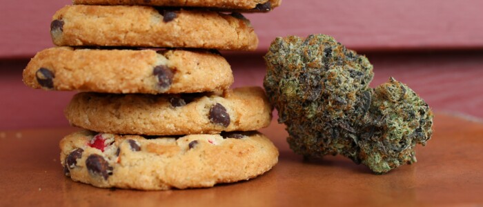 Space Cookies neben einer Cannabisblüte auf einem Holztisch