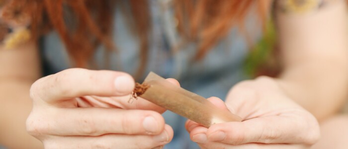 Frau mit langen roten Haaren die einen Blunt dreht