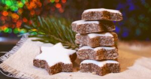 zimtsterne auf jute vor beleuchtetem weihnachtshintergrund